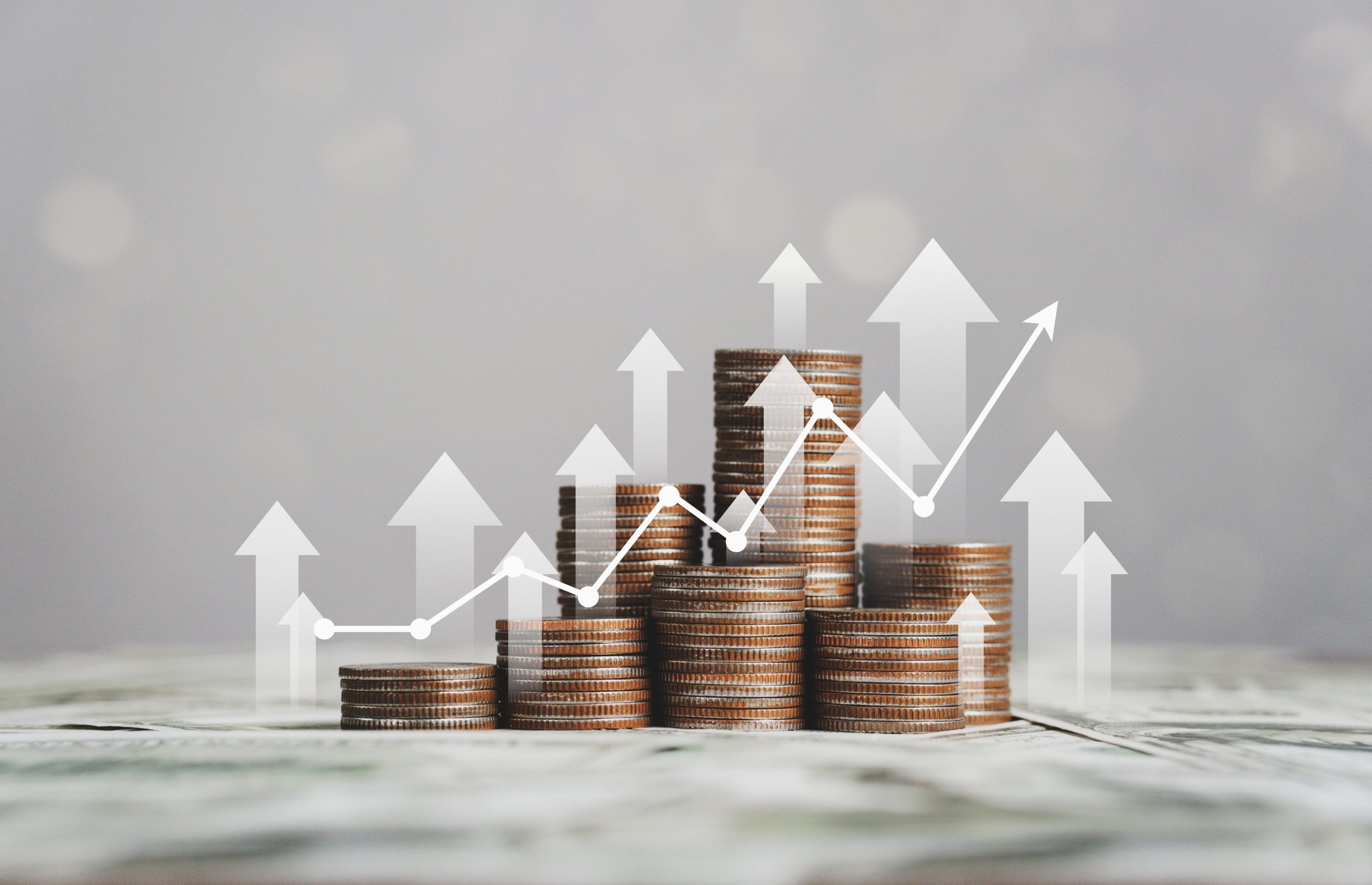 stack of silver coins with up arrows and chart business showing business growth.